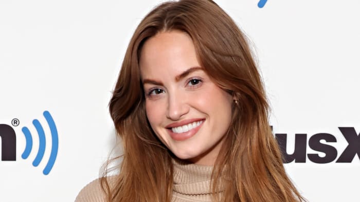 Haley Kalil poses in a tan turtle neck and smiles for the camera.